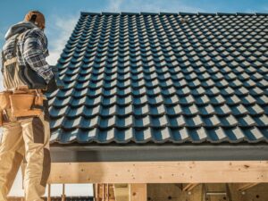 Tile Roofing Worker and the House Construction. Scaffolding on the Home Side. Industrial Theme.