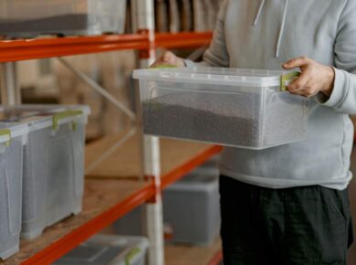 Mah hands holding box with roasted coffee beans standing on warehouse. Ready for sale